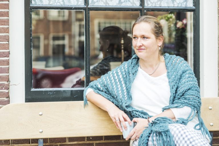 Anne-Claire Stuivenberg zittend op haar Amsterbankje in de Jordaan