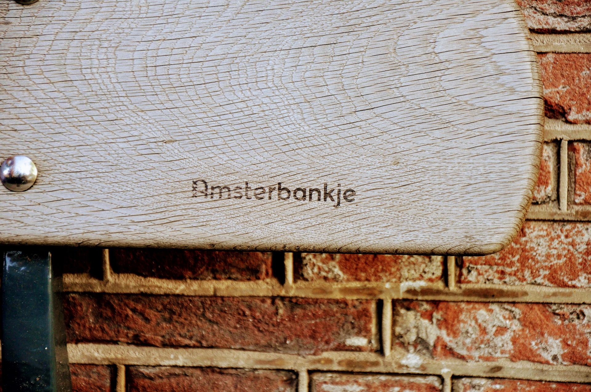 Een vergrijst gevelbankje voorzien van een Amsterbankje logo